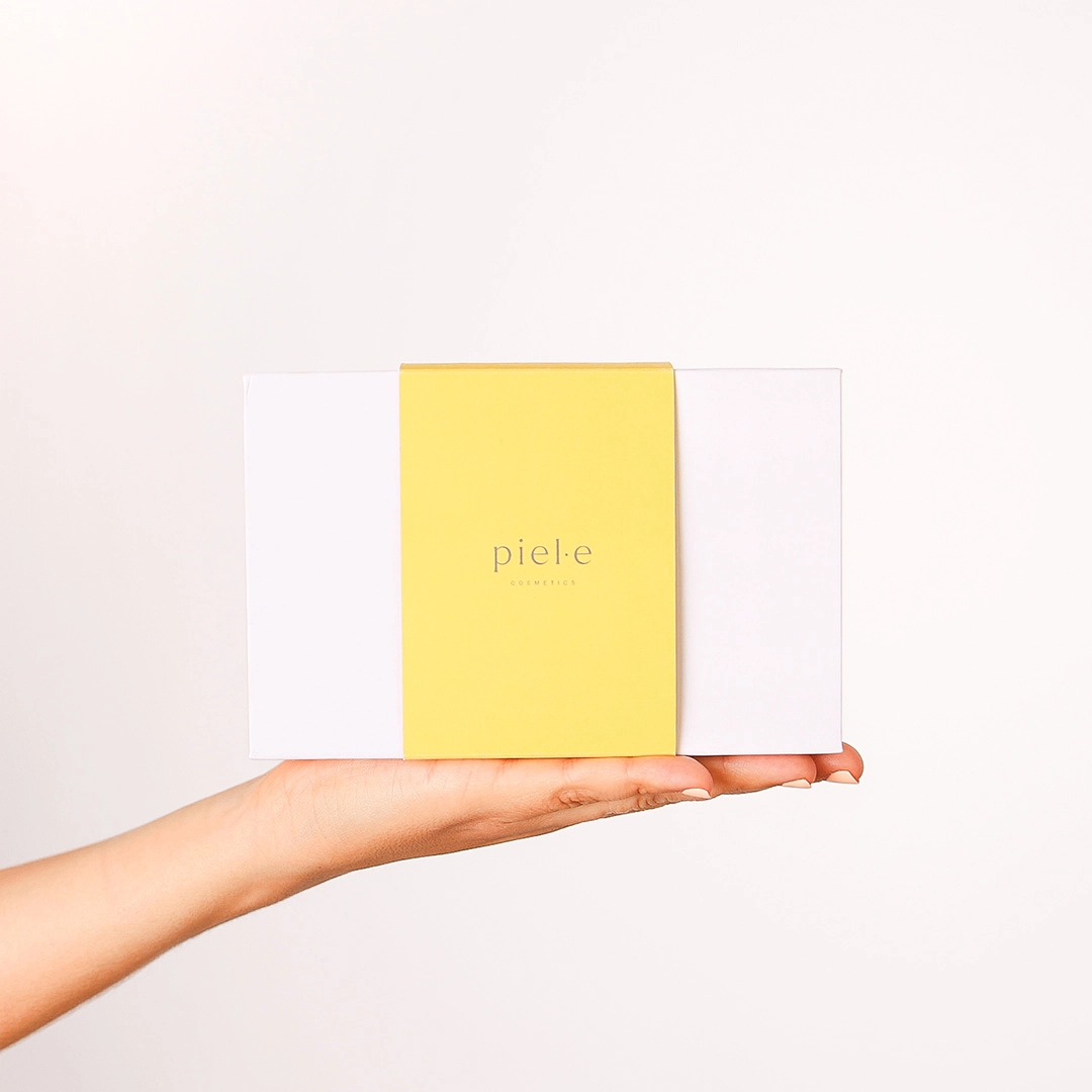 Una mano sujetando el Pack "Siénteme", una caja de muestras de productos de Piel·e Cosmetics